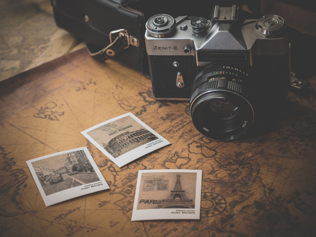 black-and-grey-dslr-camera-near-several-photos-on-brown-map-mj2nwyh3wba